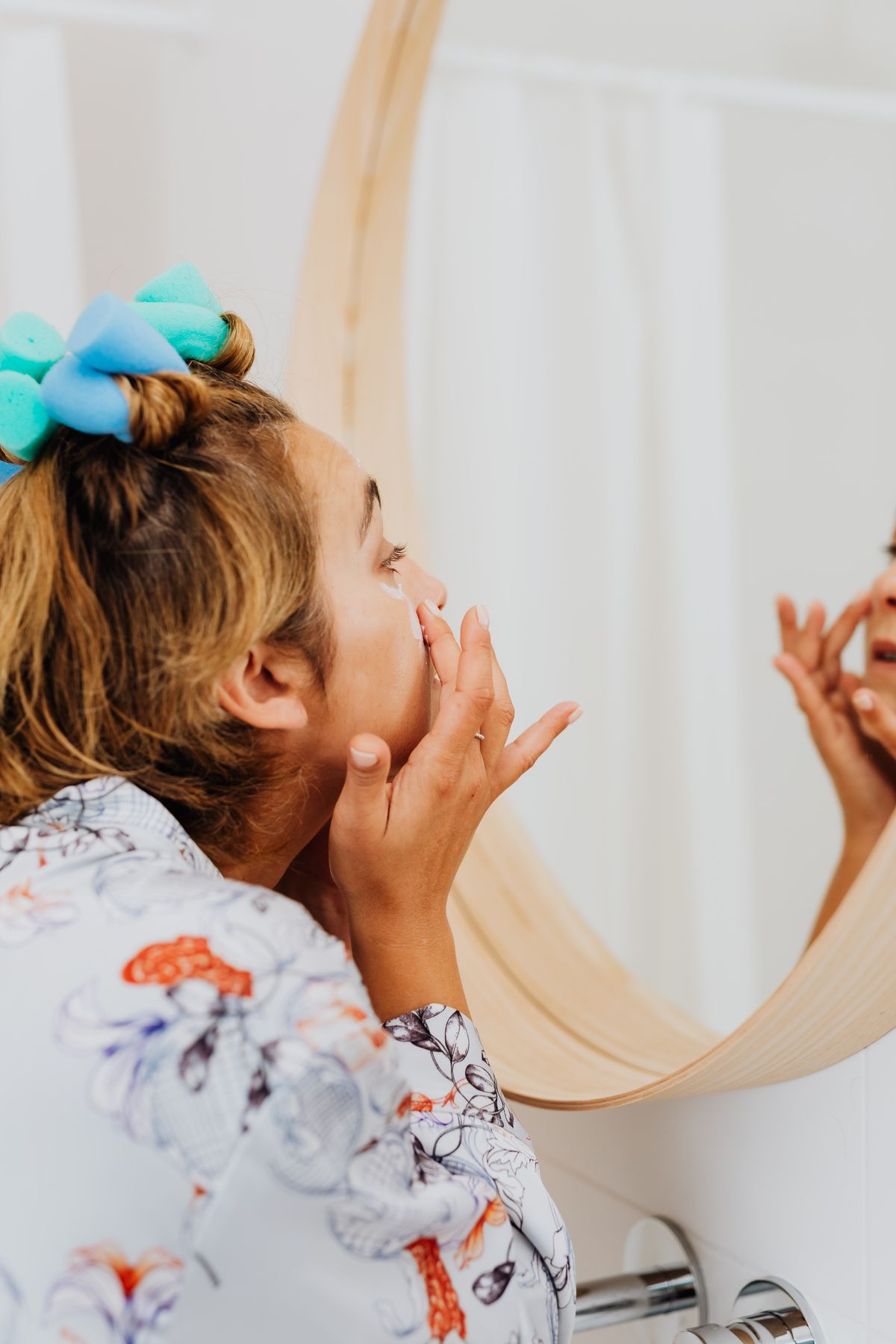 Rutina facial de día: fotografía editorial de woman applying face cream in a morning mirror routine