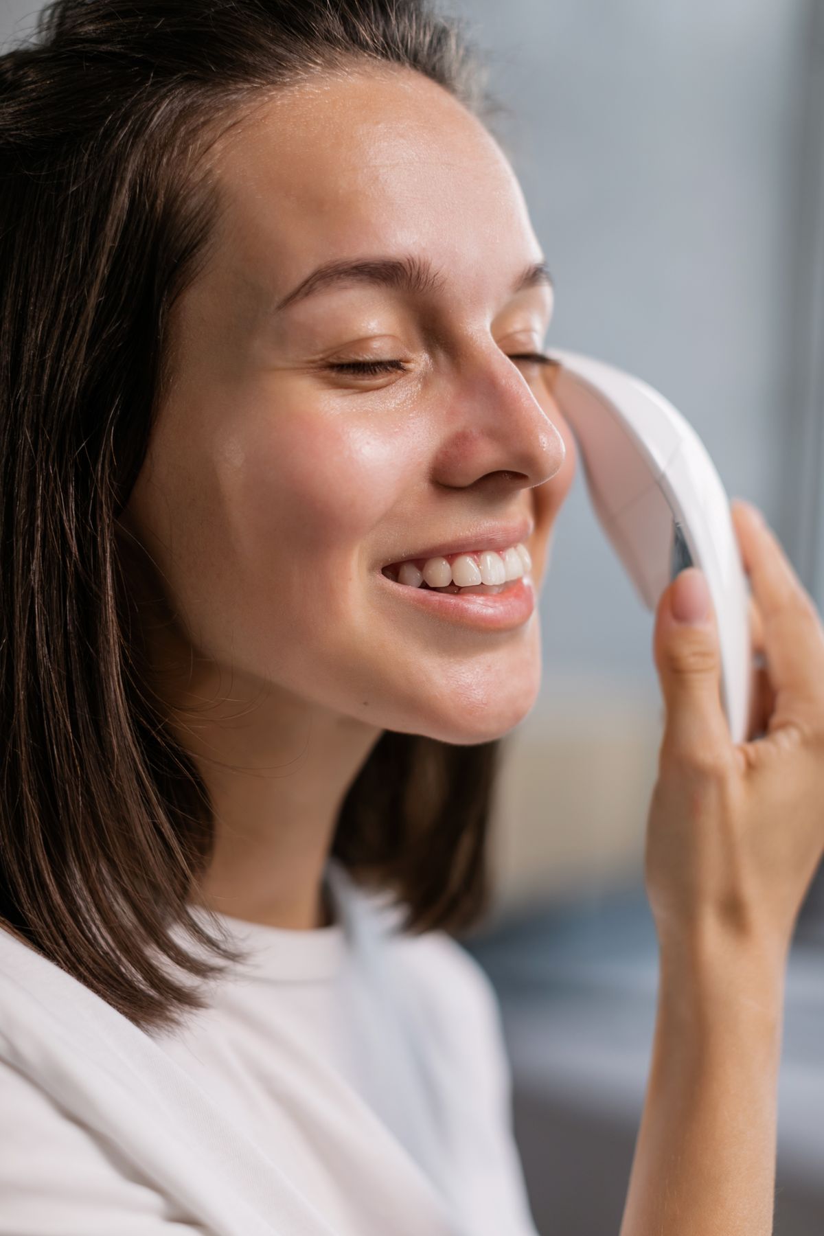 Ejercicios faciales para las mejillas: fotografía editorial de a woman using a facial massage tool on the cheek