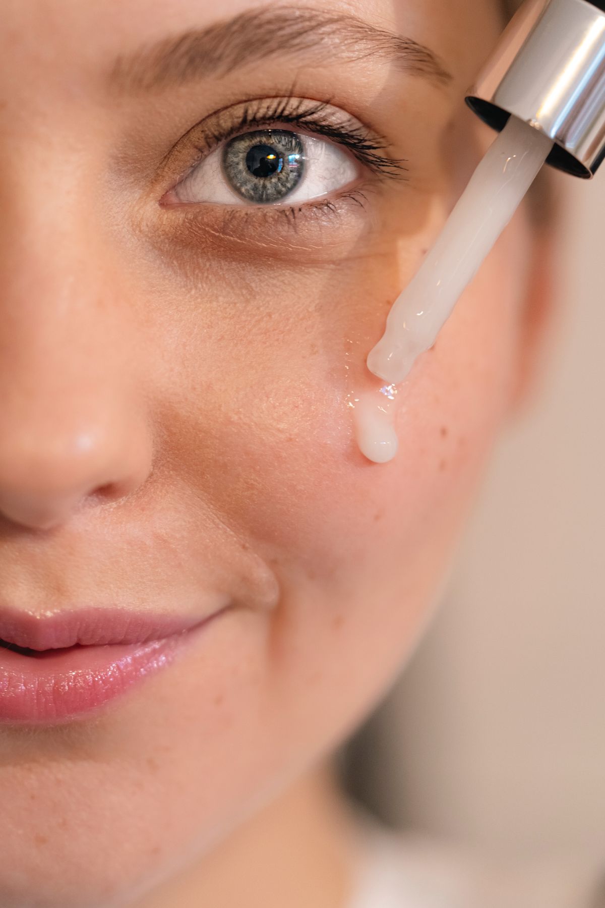 Ácido hialurónico vs colágeno: fotografía editorial de mujer aplicando sérum facial con gotero sobre el rostro